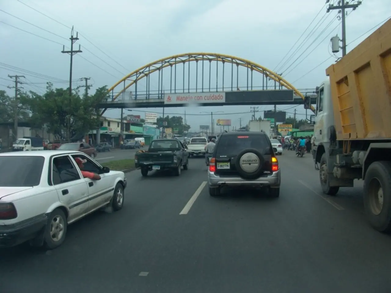 As we can see in the image there are cars, trucks, motorcycles, bridge, current polls, buildings,...