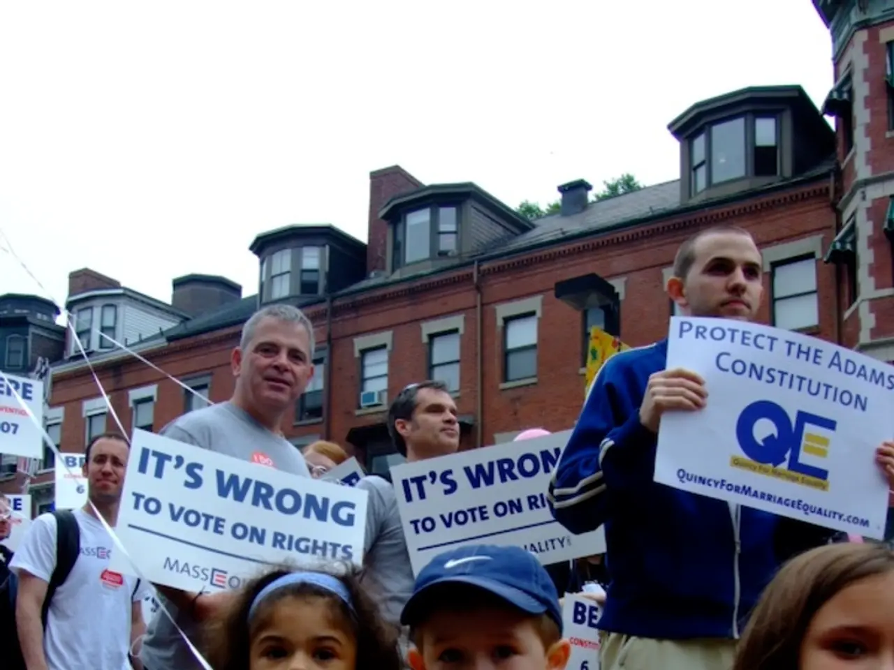 In this image I can see there are group of people who are holding boards in their hands, behind...
