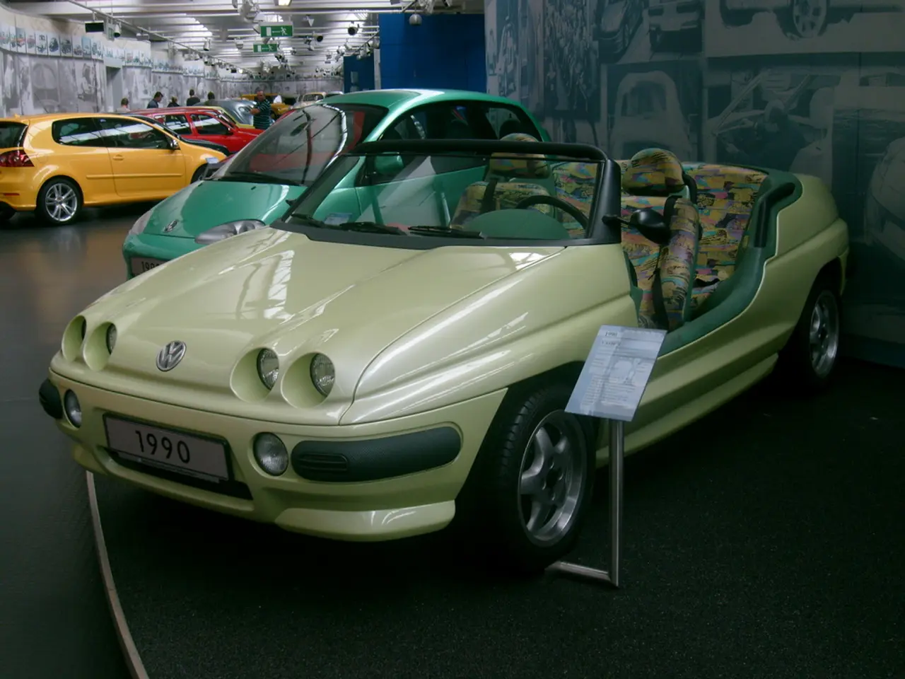 In the image there are many cars and in the background there are some people around the cars.