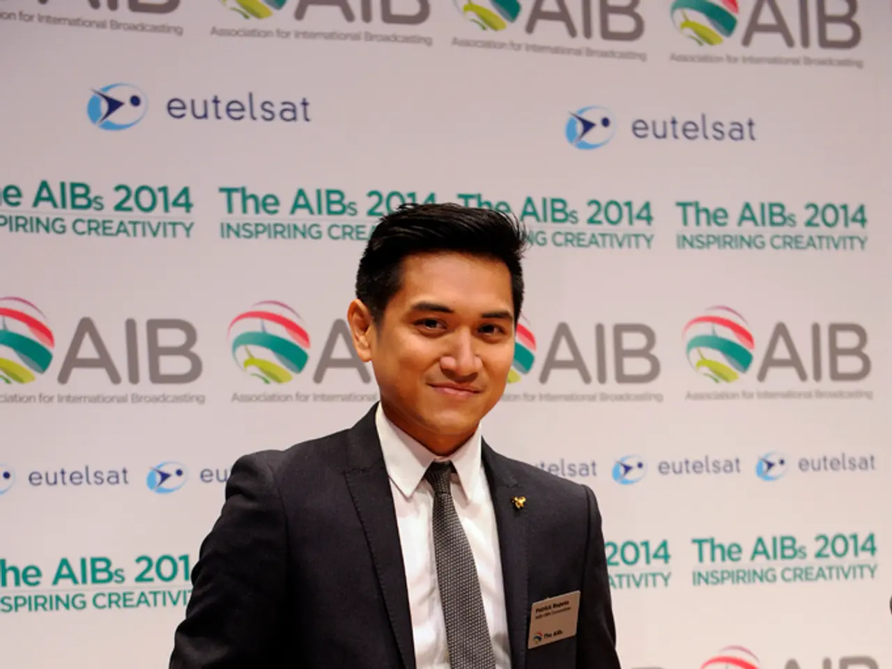 In this picture there is a person standing and smiling and he is holding the object. At the back...