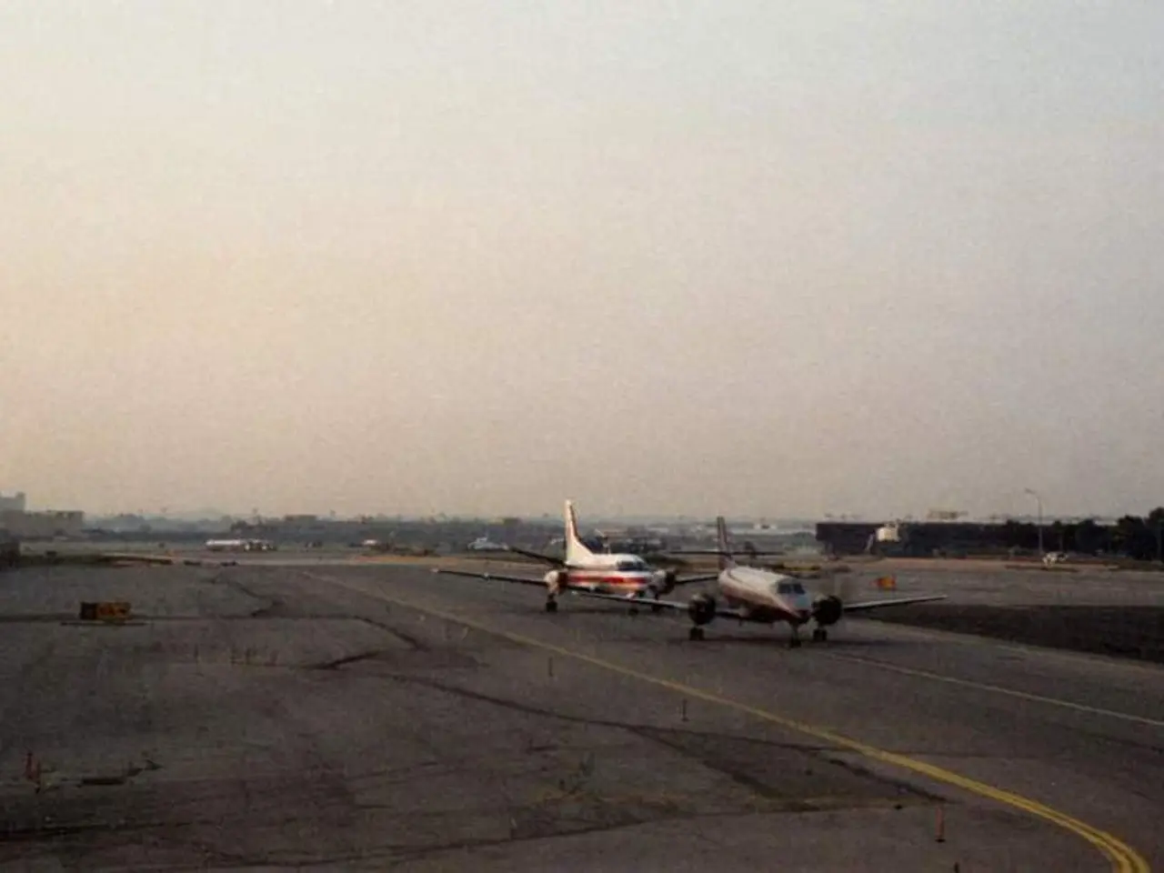This picture shows a couple of aeroplanes on the runway and we see buildings and trees and we see a...