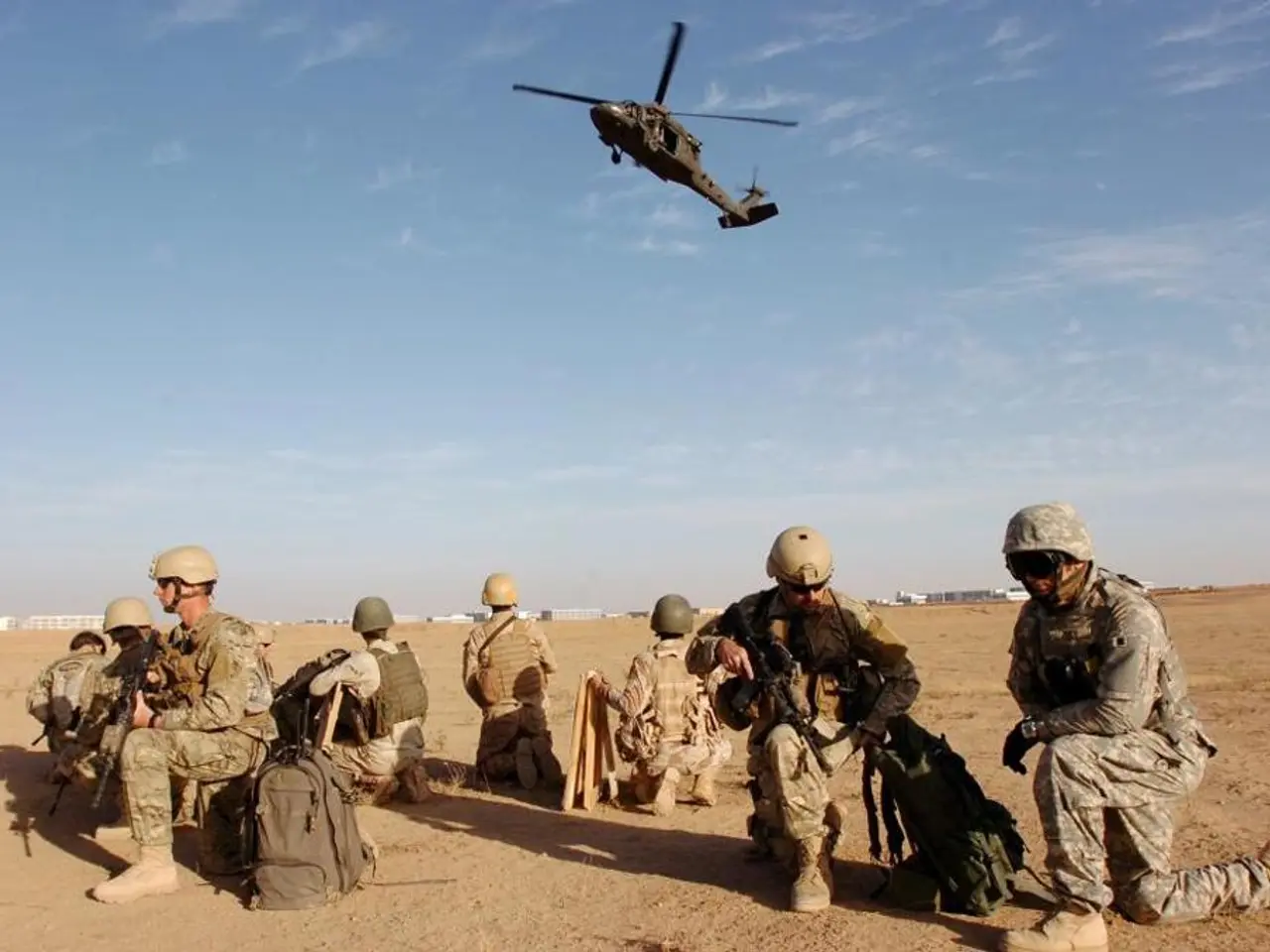 In this image we can see the army people weapons and bags on the ground. At the top we can see the...