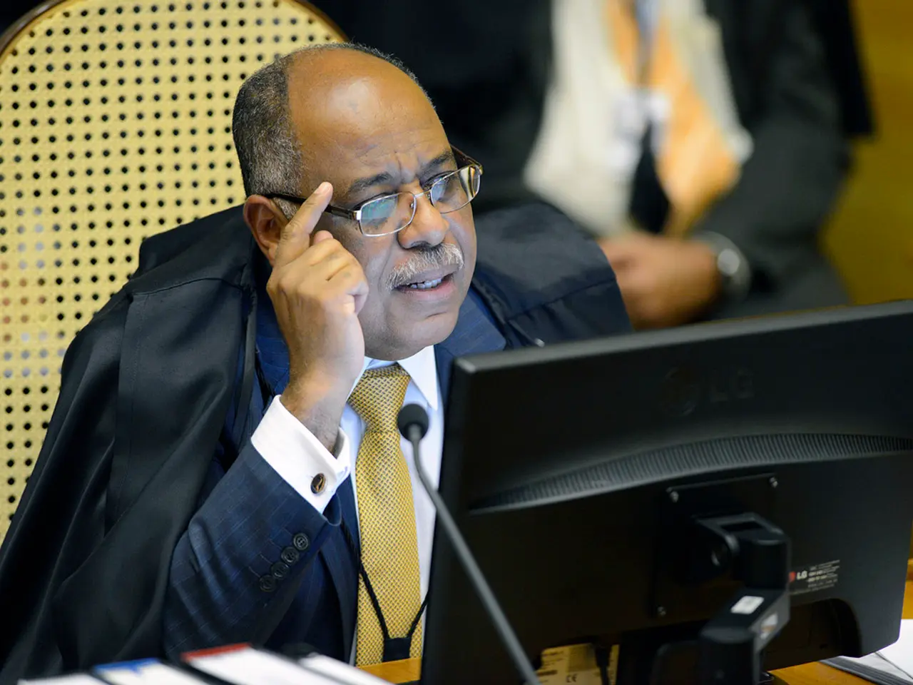 In this picture I can see there a person sitting and there is a computer in front of him. In the...