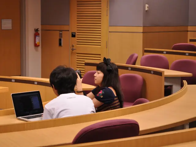 This picture is taken in a conference hall where two persons are sitting on a chair. The woman in...