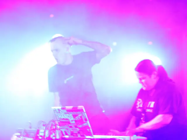 This image consists of two persons. On the right, the women wearing black T-shirt is playing the...