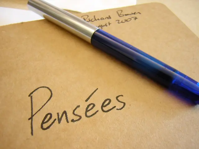 In this picture we can see a writing pad in the front, there is some text and a pen present on this...