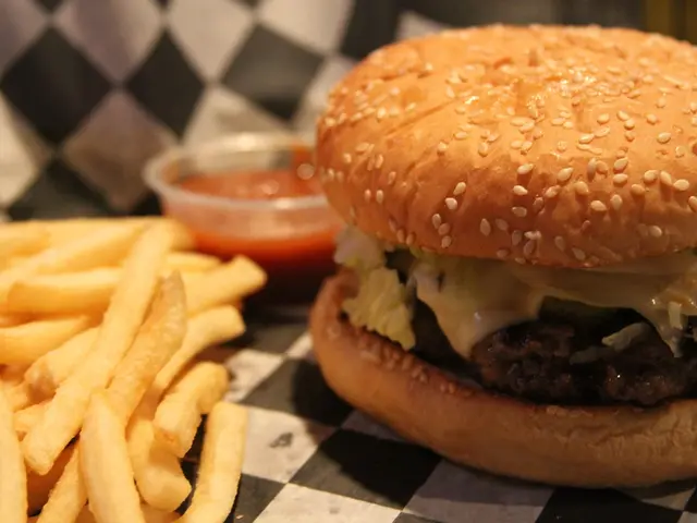 In this image we can see there is a burger, french fries and sauce.