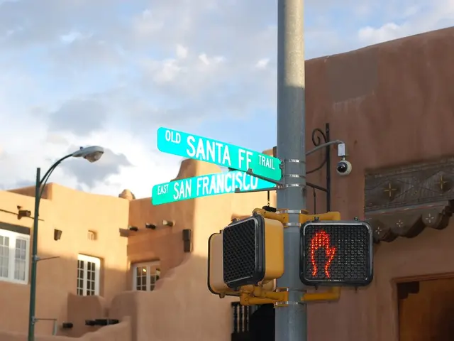 In this picture we can see name boards and signals attached to a pole, street light, buildings with...