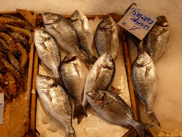 In this picture we can see there are fishes, shrimps on the wooden trays. On the right side of the...