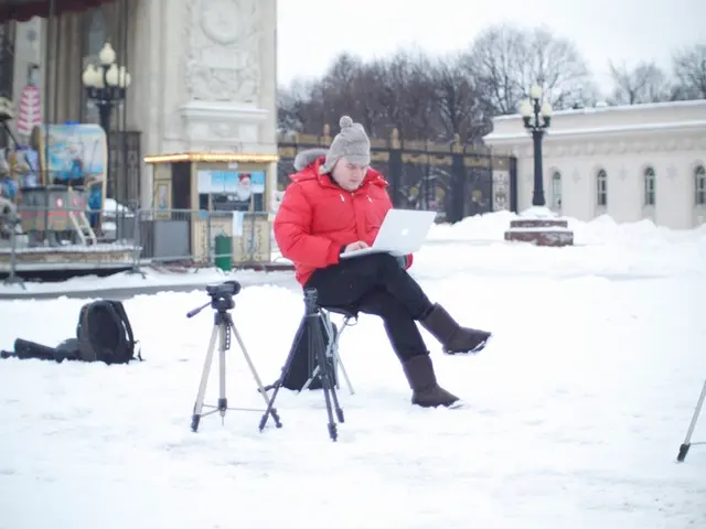 In the center of the image a person is sitting on a chair and wearing hoodie and holding laptop. In...